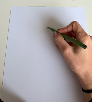 Ranka žaliu flomasteriu rašo ant balto lapo